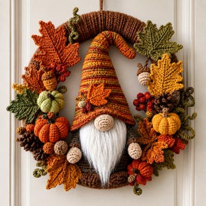Peut inclure: Une couronne circulaire ornée d'un gnome central avec un grand chapeau rayé orange et marron, une barbe en fausse fourrure blanche et des mains en crochet. La couronne est décorée de feuilles d'automne, de petites citrouilles, de glands et de pommes de pin.