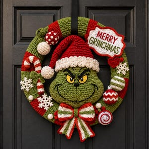 May include: A crocheted Christmas wreath featuring a green character face wearing a red and white hat. The wreath is decorated with red and white striped candy canes, white snowflakes, small spheres, and a bow. A sign reads MERRY GRINCHMAS.