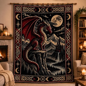 May include: A rectangular woven tapestry featuring a large red dragon perched on a cliffside overlooking a castle and mountains under a full moon. The border displays intricate Celtic knotwork, stars, and crescent moon symbols on a black background.