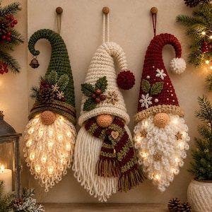 May include: Three hanging crochet gnome ornaments with pointed hats in green, cream, and red. Each gnome features a round nose, a long white beard, and integrated warm LED lights. The hats are decorated with pinecones, holly, and snowflakes.
