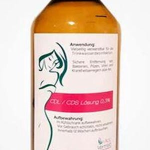 May include: A brown bottle with a red cap and a white label. The label features a green line drawing of a woman and text in German. The bottle contains a liquid and is likely a health product.