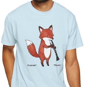 Puede incluir: Camiseta azul claro con un zorro de dibujos animados tocando el clarinete. El zorro está representado en tonos rojos y blancos, sosteniendo un clarinete negro. Las palabras "CLARINET" y "*SQUEAK" están impresas debajo.