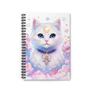 Pode incluir: Caderno espiral com uma ilustração de um gato branco com olhos azuis, uma lua crescente na testa e uma coleira roxa com um pingente de estrela. O design inclui nuvens rosa e roxas, estrelas e outros elementos celestiais.