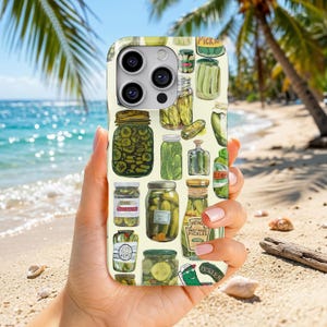 May include: A phone case with a cream-coloured background featuring a repeating pattern of various glass jars filled with green pickles, including a Heinz Sweet Mixed Pickles bottle, with different shapes and sizes of pickles illustrated throughout.