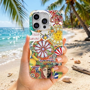 May include: A smartphone case featuring a vibrant Mediterranean-inspired pattern with lemons, a yellow sun, a red and white wheel design, and a stylized face. The text ciao amore is printed in red script against a white background with colorful floral motifs.