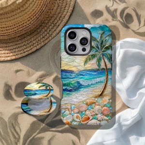 Puede incluir: Una funda y un soporte para teléfono con un diseño de playa, que incluye una palmera, olas del océano y conchas marinas. La funda es azul, blanca y marrón. El soporte para teléfono tiene un diseño a juego. Un sombrero de paja y tela blanca están en el fondo.