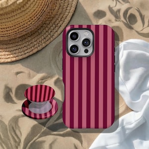 May include: A smartphone case and a matching collapsible phone grip, both featuring a vertical striped pattern in alternating shades of dark burgundy and muted rose pink. The case has a cutout for a triple-lens camera system on the back.