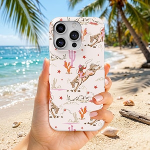 May include: A light pink smartphone case featuring a repeating pattern of western-themed illustrations including cowboys riding bucking horses, various cacti, small red stars, and desert mountain landscapes printed across the entire surface.