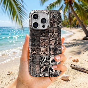 Puede incluir: Una funda para smartphone con una cuadrícula de azulejos cuadrados con patrones de animales en blanco y negro, incluyendo manchas de leopardo y texturas de piel de serpiente. La funda tiene un recorte para una cámara de tres lentes.