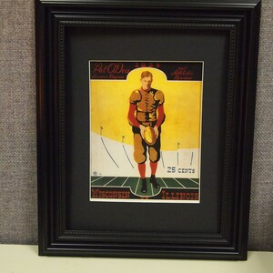 May include: A framed vintage poster advertising a 1937 football game between the University of Wisconsin and the University of Illinois. The poster features a football player in a brown and white uniform holding a football. The poster is titled "Pat O'Dea and Athletic Review" and costs 25 cents.