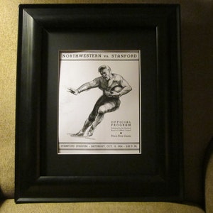 May include: Black and white framed print of a football player running with the ball. The print is titled "Northwestern vs. Stanford" and includes the text "Official Program" and "Price Five Cents".