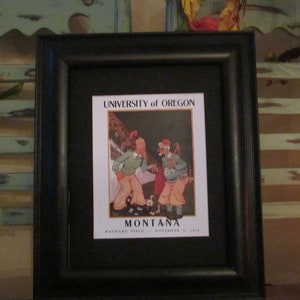 May include: Framed print featuring a vintage illustration of a football game between the University of Oregon and Montana. The artwork, set against a black frame, displays two figures in vintage attire, with the text "UNIVERSITY of OREGON" and "MONTANA".