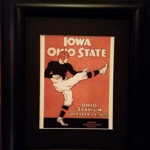 May include: A vintage poster advertising a football game between Iowa and Ohio State. The poster features a black and white illustration of a football player kicking the ball. The text on the poster reads "Iowa Ohio State", "Ohio Stadium", "October 24, 1925", and "Price Twenty-Five Cents".