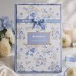 May include: A rectangular gift box with a floral pattern in shades of blue and white. The box is tied with a blue ribbon and bow. The text "Be Wonderful" is visible on a label. The background includes flowers and decorative elements.