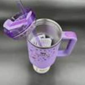 Puede incluir: Una m&aacute;quina el&eacute;ctrica para hacer sopa, de color morado y plateado, con un asa y una tapa transparente. La tapa est&aacute; abierta, revelando el interior. La m&aacute;quina est&aacute; sobre una superficie de acero inoxidable.