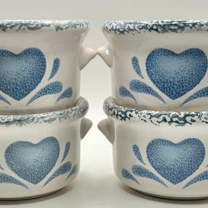 May include: Four white ceramic soup bowls with blue heart designs and handles. The bowls have a speckled blue and white rim and a blue heart in the center, surrounded by blue water droplet designs.