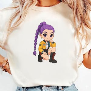 Pode incluir: Camiseta branca com uma ilustra&ccedil;&atilde;o de desenho animado de uma pessoa com cabelo roxo em uma tran&ccedil;a longa. A personagem usa uma jaqueta amarela, shorts pretos e botas pretas. O design tem uma est&eacute;tica jovem inspirada em anime.
