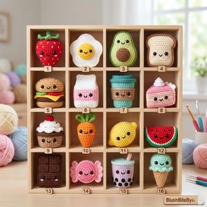 May include: A wooden display case featuring sixteen crocheted food items. The collection includes a strawberry, egg, avocado, toast, burger, milk carton, coffee cup, cake, cupcake, carrot, lemon, watermelon slice, chocolate bar, candy, boba tea, and ice cream cone.