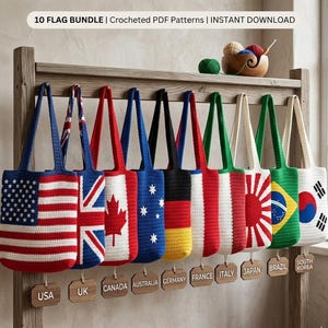 May include: A collection of ten crocheted tote bags, each displaying a different national flag design. The flags include the USA, UK, Canada, Australia, Germany, France, Italy, Japan, Brazil, and South Korea. The bags are suspended from a wooden rack.