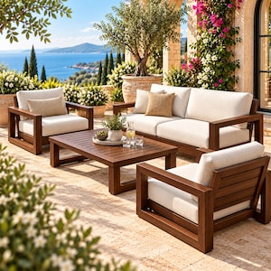 May include: An outdoor furniture set featuring a dark wood sofa and two matching armchairs with thick, cream-colored cushions. A rectangular slatted wood coffee table sits in the center, holding a small potted plant, a glass carafe, and glasses.