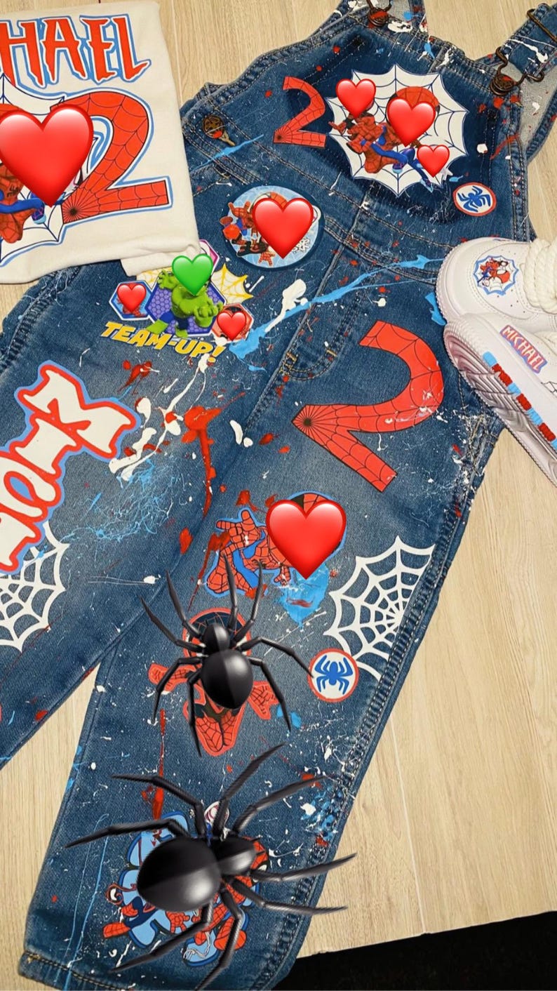 May include: A denim overall set with a matching t-shirt and sneakers. The overalls and t-shirt feature a Spider-Man theme with the number "2", spiderwebs, and the text "HAEL" and "TEAM UP!". The sneakers have the name "MICHAEL" on them.