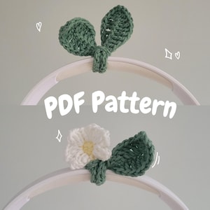 Op de afbeelding: Een handgemaakte gehaakte mobiel met een groen bladerontwerp en een witte bloem. De tekst "PDF Pattern" staat op de afbeelding. De mobiel is ontworpen om aan een cirkelvormig frame te hangen.