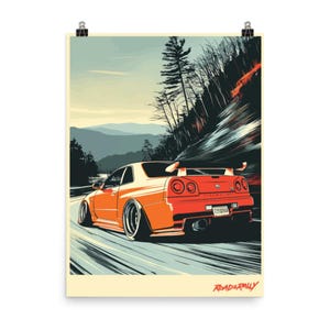 以下が含まれることがあります： クリーム色の背景にオレンジ色のスポーツカーのアートプリント。車は山を背景に曲がりくねった道に描かれています。プリントには、下部に「ROAD & RALLY」の文字が含まれています。