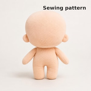 May include: A beige plush doll base with a large round head, small ears, and a simple body shape. The text Sewing pattern is printed in black in the upper right corner. The doll has a smooth, uniform texture and a neutral, featureless face.
