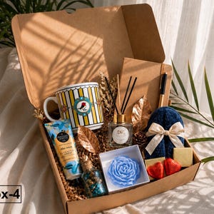 K&ouml;nnte beinhalten: Eine Geschenkbox mit der Aufschrift Box-4 enth&auml;lt eine gelb-wei&szlig; gestreifte Tasse mit Vogelmotiv, eine Handcremetube, einen Raumduft-Diffusor, ein Notizbuch mit Stift, eine blaue rosenf&ouml;rmige Kerze, zwei herzf&ouml;rmige Pralinen und blaue Hausschuhe.