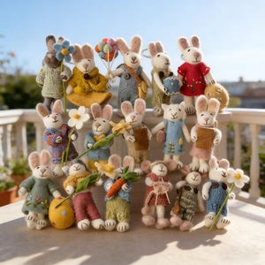 May include: A group of handcrafted bunny figures, each dressed in individual outfits and carrying accessories. The bunnies are made from soft, textured materials and feature a range of colours, including pastels and earthy tones. Some hold flowers, carrots, or balloons, creating a charming display.