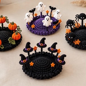 May include: Four round, crocheted Halloween-themed displays. One features orange pumpkins, one has white ghosts and black bats, one displays black spiders and orange webs, and one showcases black witch hats with purple bands and orange stars.