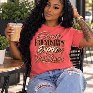 May include: A coral-colored short-sleeve t-shirt featuring the text "Some FRIENDSHIPS Expire. Dont Renew!" in a stylized brown and gold font with a small heart graphic, paired with light blue distressed denim jeans with ripped knee details.