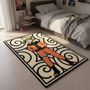 May include: A rectangular rug featuring a cartoon character in an orange and black outfit, with a cream background and black swirling patterns. The rug has a black border and is placed on a light wood floor. The character is lying down.