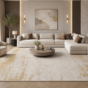 May include: A modern living room featuring a large, off-white sectional sofa with brown accent pillows. A round coffee table sits on a cream-colored rug with gold accents. The room includes a curved armchair, a tree in a pot, and a painting.