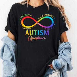 May include: Black t-shirt with a rainbow infinity symbol and the words "ADVOCATE, EDUCATE, ACCOMMODATE, INCLUDE" around it. The word "AUTISM" is in rainbow colors, and "Acceptance" is written below it in a cursive font.
