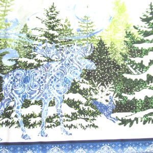 May include: A winter-themed fabric featuring a moose and deer in a snowy forest. The animals are patterned with blue and white designs. Snow-covered evergreen trees fill the background, with a blue border at the bottom.