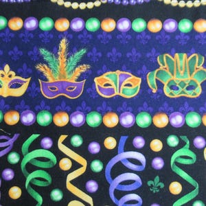 May include: Purple, green, and gold Mardi Gras themed fabric with a repeating pattern of beads, masks, and fleur-de-lis.