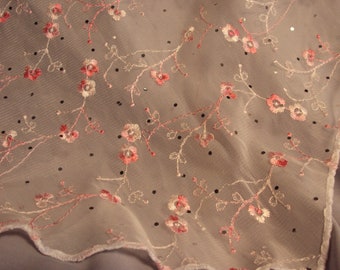 Pink embroidered flowers on a white triangular scarf