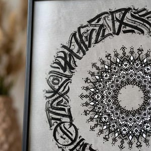 Peut inclure: Œuvre d'art encadrée avec un cadre noir, représentant un mandala noir et blanc. L'œuvre présente un motif géométrique central et un motif calligraphique circulaire. Le fond est gris clair.