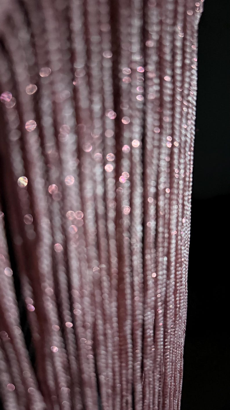 Peut inclure: Une s&eacute;rie de brins verticaux de couleur rose poudr&eacute; dot&eacute;s d'une subtile finition m&eacute;tallique scintillante. La texture se compose de fils fins et &eacute;troitement tiss&eacute;s cr&eacute;ant un motif lin&eacute;aire, refl&eacute;tant la lumi&egrave;re avec des reflets bokeh doux.