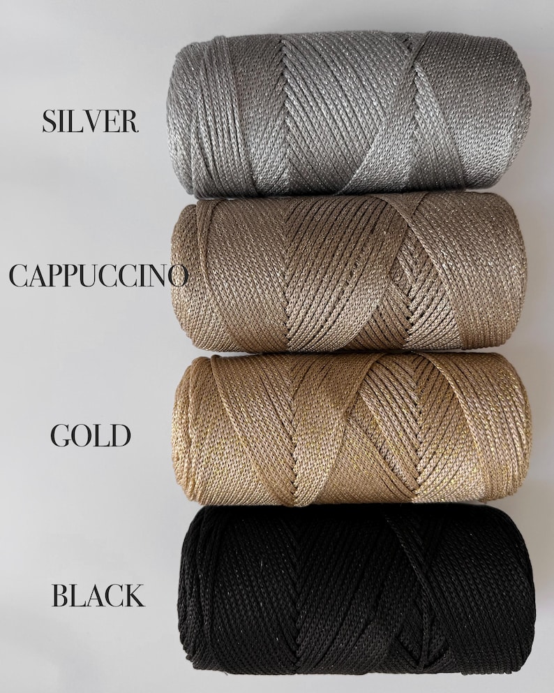 Peut inclure: Quatre bobines cylindriques de cordon m&eacute;tallique dispos&eacute;es verticalement. Les couleurs sont &eacute;tiquet&eacute;es SILVER, CAPPUCCINO, GOLD et BLACK. Chaque bobine pr&eacute;sente une texture tress&eacute;e &eacute;troitement enroul&eacute;e avec un &eacute;clat distinct.