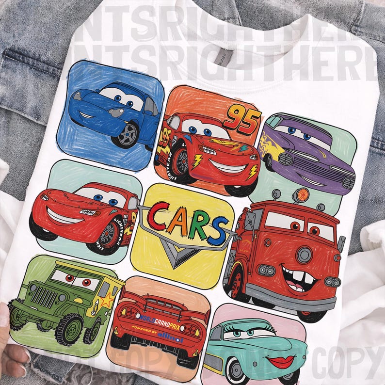 May include: White sweatshirt featuring a colorful graphic of various cartoon cars. The design includes images of Lightning McQueen, Mater, and other characters from the animated movie "Cars". The word "CARS" is also displayed.