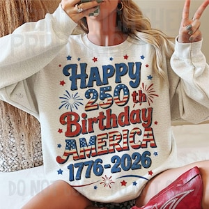 May include: A light gray sweatshirt with a patriotic design celebrating America's 250th birthday. The design features the words "Happy 250th Birthday AMERICA 1776-2026" in red, white, and blue, with star and firework accents.