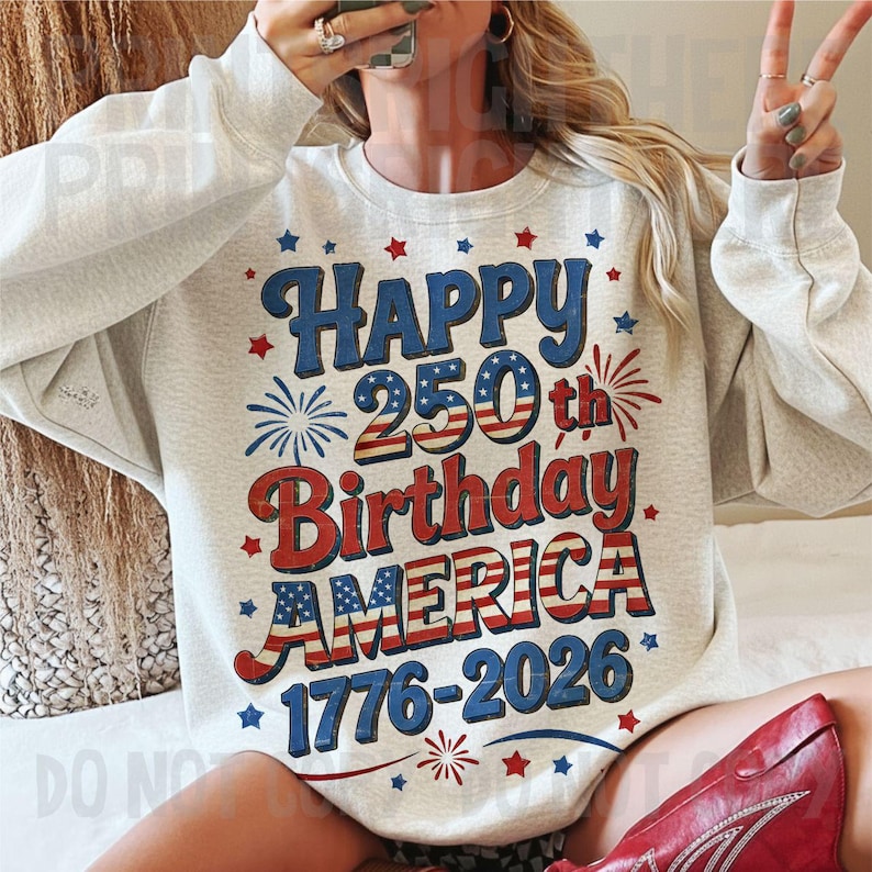 May include: A light gray sweatshirt with a patriotic design celebrating America's 250th birthday. The design features the words "Happy 250th Birthday AMERICA 1776-2026" in red, white, and blue, with star and firework accents.