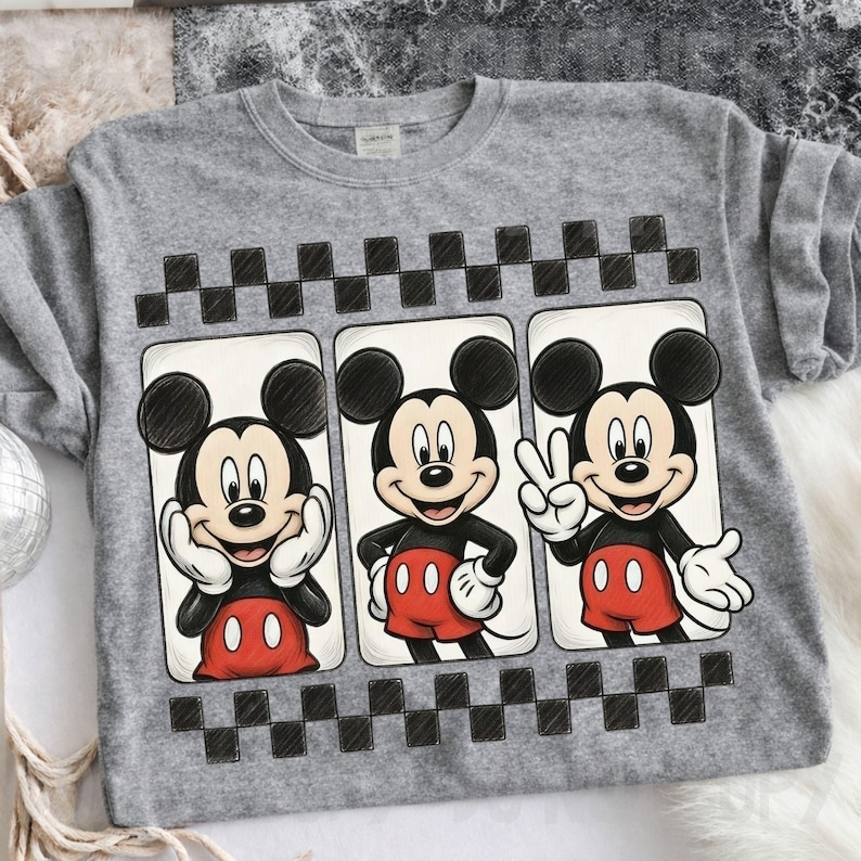 May include: A gray sweatshirt featuring three panels with Mickey Mouse illustrations. Each panel shows Mickey in a different pose, with a black and white checkered pattern above and below the panels. Mickey is wearing red shorts and white gloves.