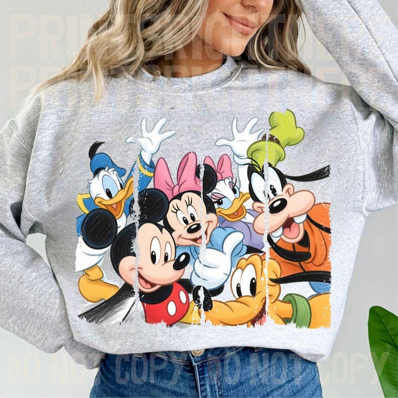 May include: A light gray sweatshirt featuring a colorful graphic of Disney characters including Mickey Mouse, Minnie Mouse, Donald Duck, Daisy Duck, and Goofy. The graphic has a distressed, vintage look.