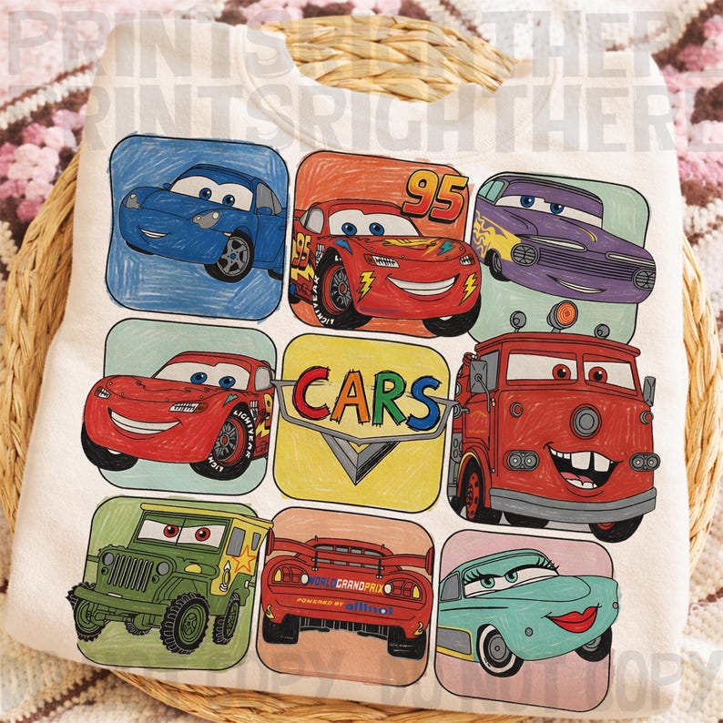 May include: White sweatshirt featuring colorful cartoon car illustrations. The design includes various car characters in square frames, with the word "CARS" in a central logo. The overall style is reminiscent of a children's drawing.