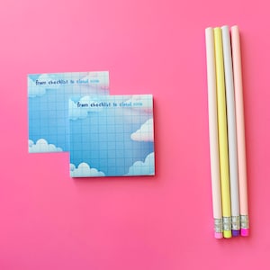 May include: Two square sticky notes with a blue sky and cloud design, and the text "from checklist to cloud nine". Five pastel-colored pencils with erasers are arranged on a bright pink background.