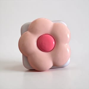 Könnte beinhalten: Ein Set aus drei Keramikbechern mit gesprenkelter, matter Oberfläche. Die Becher sind in Creme-, Hellgrau- und Dunkelgrautönen gehalten. Jeder Becher hat ein schlichtes, minimalistisches Design.