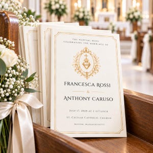 Puede incluir: Una pila de programas de boda color crema con bordes de lámina dorada y un emblema central dorado de un sagrado corazón. El texto dice: The Nuptial Mass celebrating the marriage of Francesca Rossi & Anthony Caruso, July 17, 2028, at 2 o'clock, St. Cecilia Catholic Church, Boston, Massachusetts.